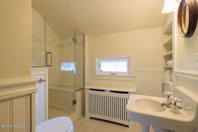 bathroom with radiator, sink, wood-type flooring, toilet, and a shower with shower door