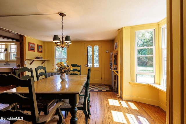 dining space featuring light wood-type flooring and an inviting chandelier