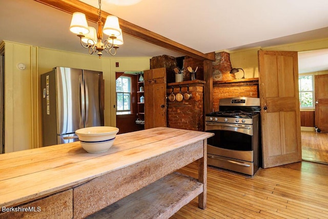 kitchen with an inviting chandelier, beamed ceiling, pendant lighting, appliances with stainless steel finishes, and light wood-type flooring