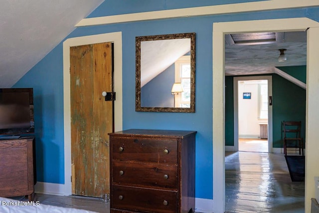 interior space with wood-type flooring, lofted ceiling, and radiator