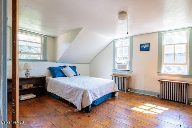 bedroom with vaulted ceiling, radiator heating unit, cooling unit, and dark hardwood / wood-style floors