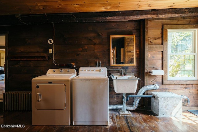 clothes washing area featuring wood walls, sink, wood-type flooring, and independent washer and dryer