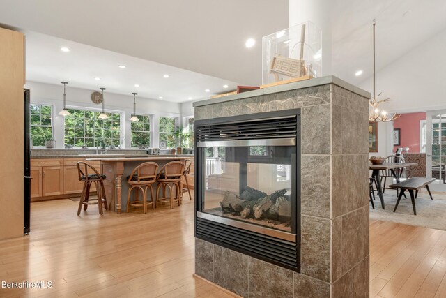 2017 Monterey Rd, Otis, MA 01253 - kitchen featuring light wood finished floors, recessed lighting, a breakfast bar, light brown cabinets, and a multi sided fireplace