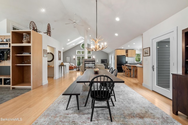 2017 Monterey Rd, Otis, MA 01253 - dining room featuring light wood finished floors, vaulted ceiling, ceiling fan, a chandelier, and a glass covered fireplace