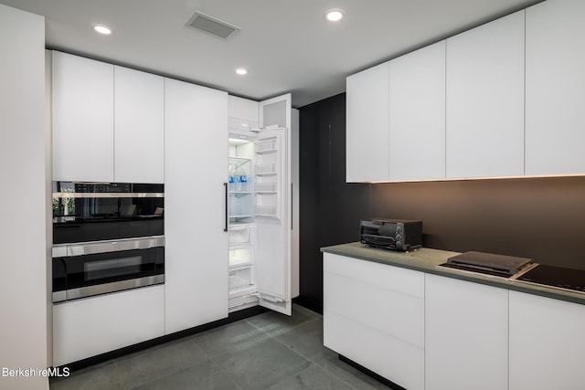 kitchen featuring white cabinets, dark tile patterned floors, and double oven