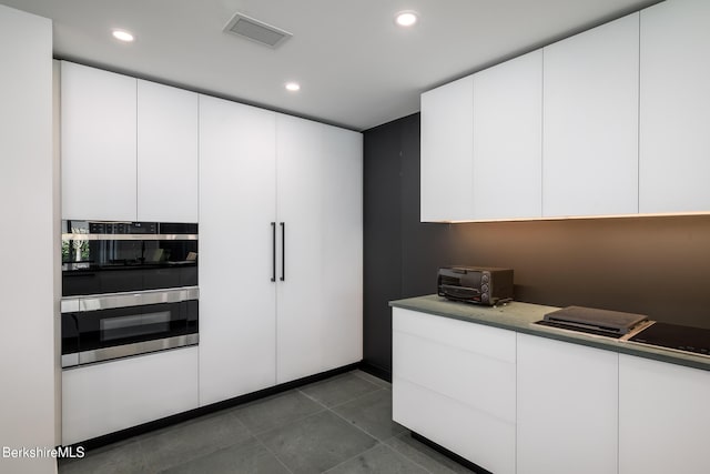 kitchen featuring dark tile patterned floors, white cabinetry, and double oven