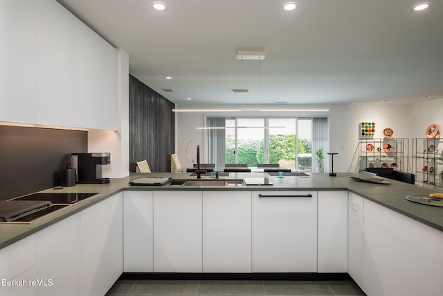 kitchen with kitchen peninsula, white cabinetry, and dark tile patterned floors