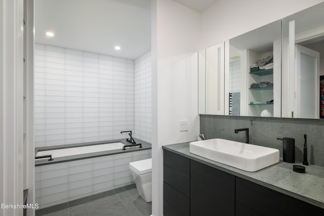 bathroom featuring tile patterned floors, tiled bath, vanity, and toilet