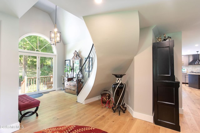 foyer entrance featuring baseboards, high vaulted ceiling, a chandelier, and light wood-style floors