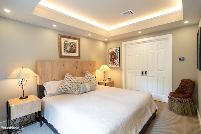 carpeted bedroom with visible vents, a raised ceiling, ornamental molding, a closet, and recessed lighting