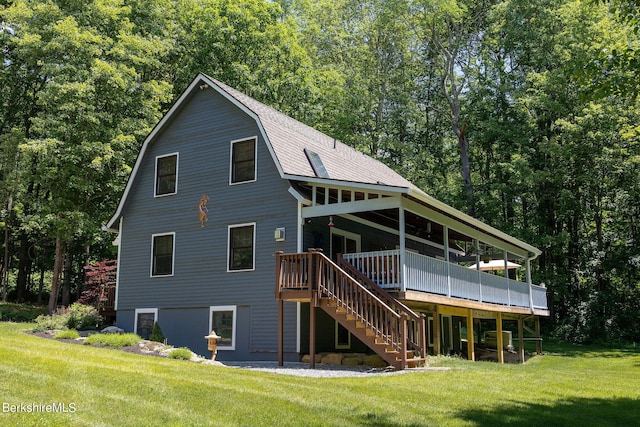 rear view of property featuring a shingled roof, a gambrel roof, stairway, a lawn, and a wooden deck