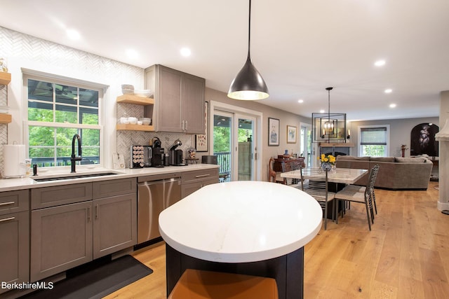 kitchen featuring dishwasher, gray cabinetry, light wood-style floors, open shelves, and a sink