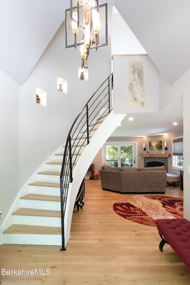 staircase with a fireplace, a towering ceiling, and wood finished floors