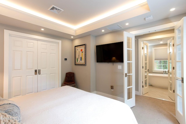 carpeted bedroom featuring a tray ceiling, french doors, and visible vents