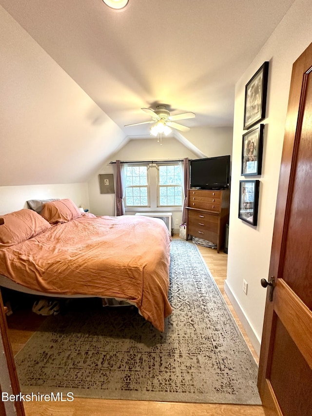 bedroom with light wood-type flooring, lofted ceiling, ceiling fan, and baseboards