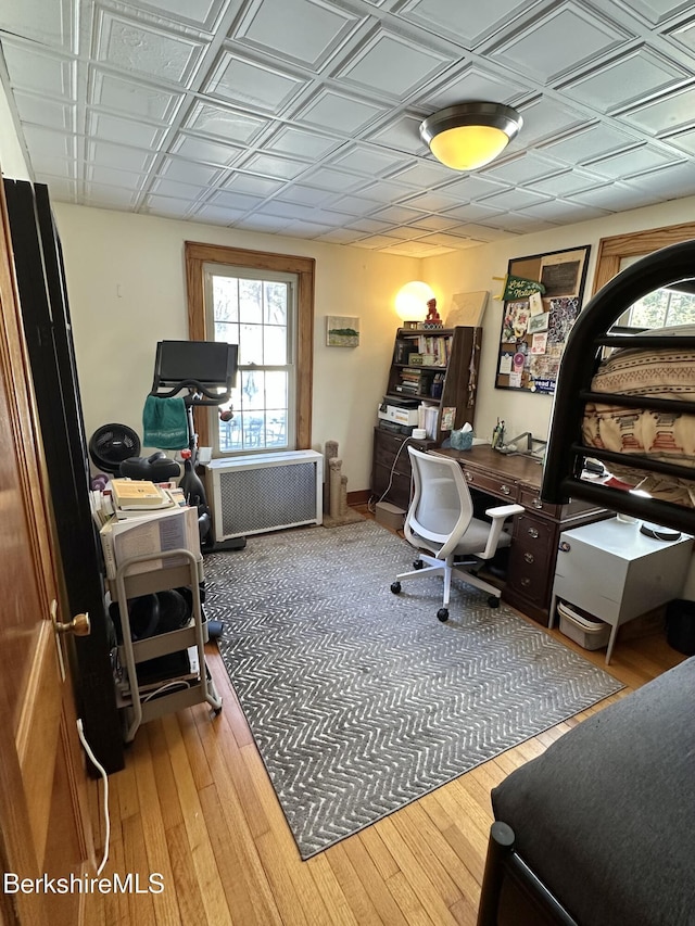 home office featuring radiator, light wood-style floors, and an ornate ceiling