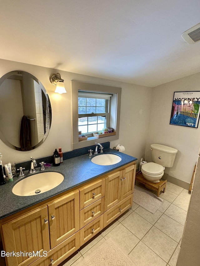 bathroom featuring tile patterned flooring, a sink, toilet, and double vanity