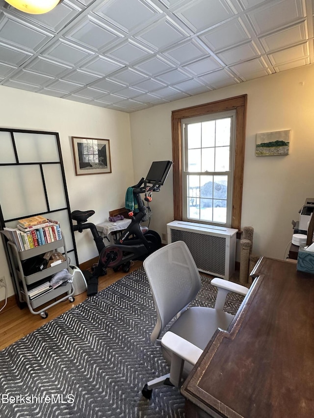 home office with radiator heating unit and wood finished floors