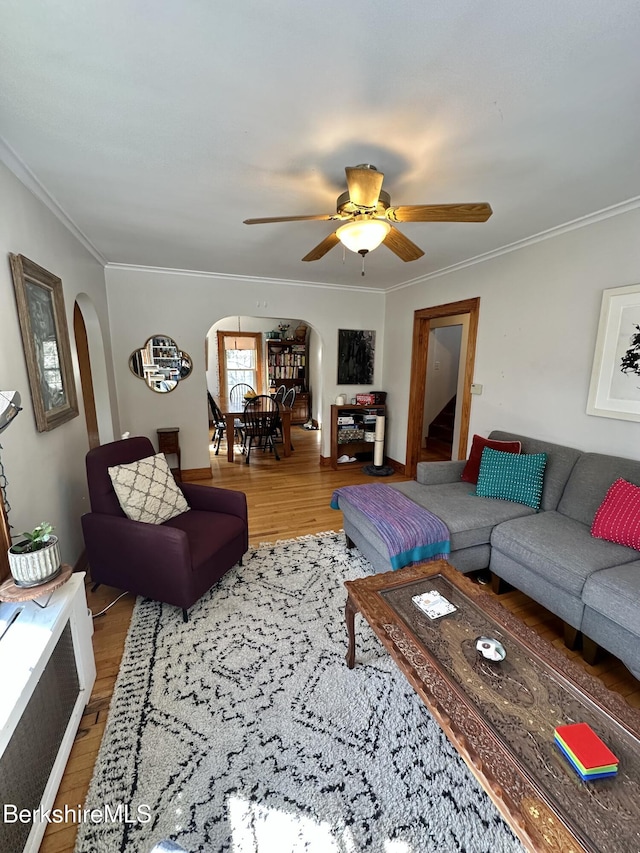 living area with light wood finished floors, arched walkways, and crown molding