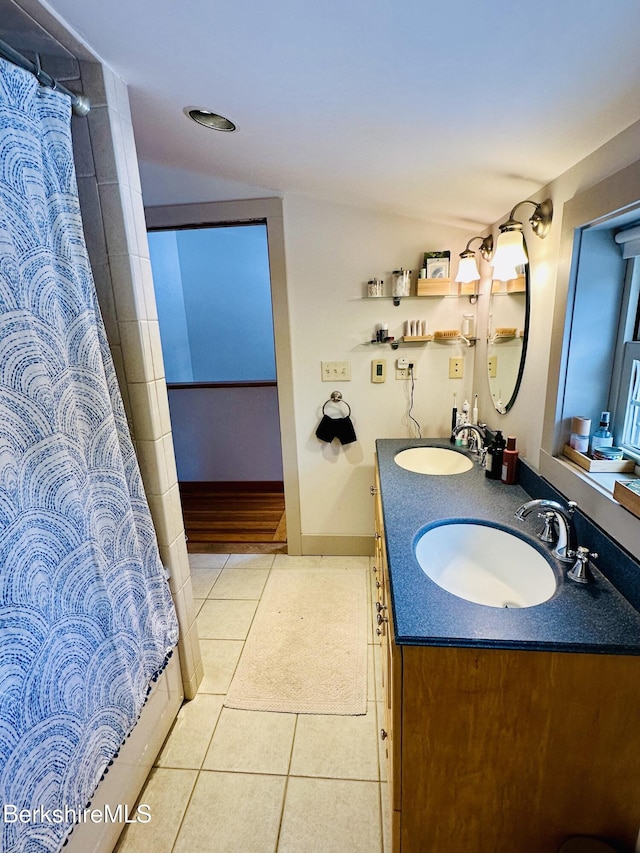 bathroom with double vanity, tile patterned flooring, baseboards, and a sink