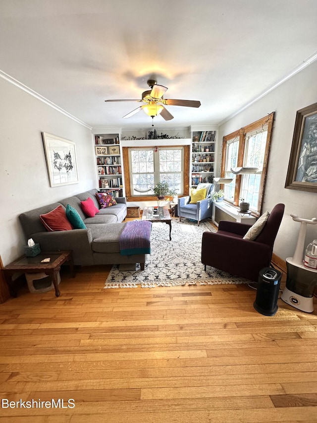 living area with ornamental molding, light wood finished floors, a ceiling fan, and built in features