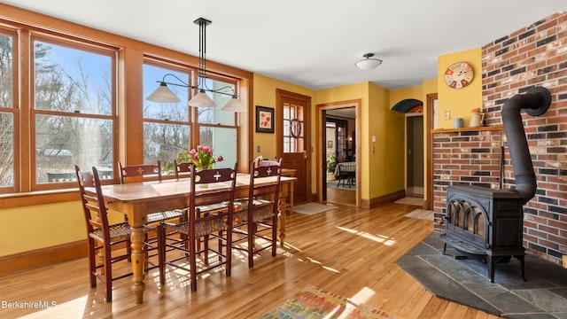 dining room featuring a wood stove, baseboards, arched walkways, and wood finished floors