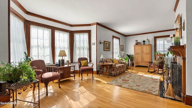 sitting room featuring light wood finished floors, a fireplace, and ornamental molding