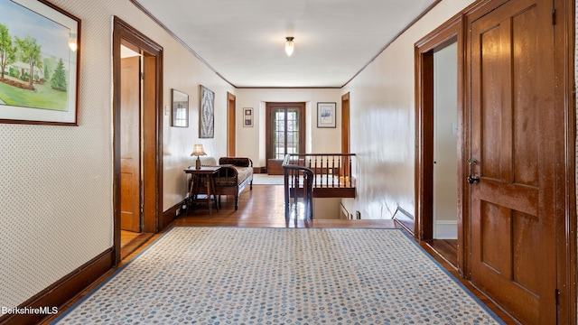 hall with baseboards, crown molding, an upstairs landing, and wallpapered walls