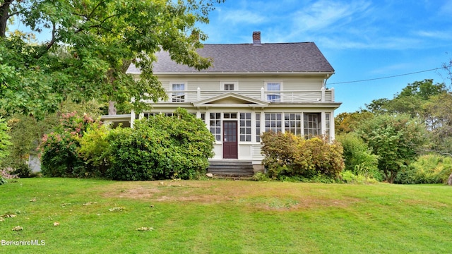 view of front of house with a front yard, a sunroom, a chimney, and entry steps