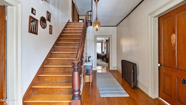 foyer entrance with baseboards, stairway, light wood-type flooring, radiator, and wallpapered walls