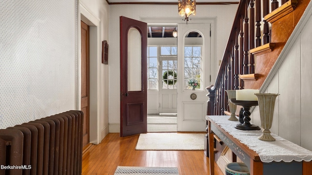 foyer entrance featuring stairs, wood finished floors, radiator heating unit, and wallpapered walls