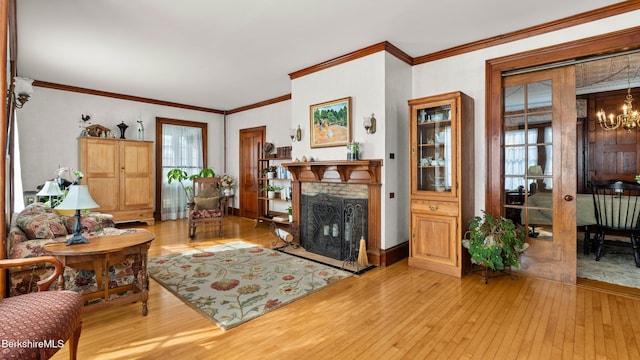 living room featuring ornamental molding, light wood-type flooring, a fireplace, and an inviting chandelier