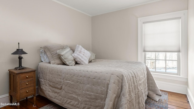 bedroom featuring baseboards, wood finished floors, and ornamental molding