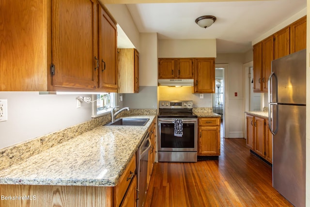 30 Belvidere Ave, Pittsfield, MA 01201 - kitchen featuring stainless steel appliances, under cabinet range hood, brown cabinets, dark wood finished floors, and light stone countertops