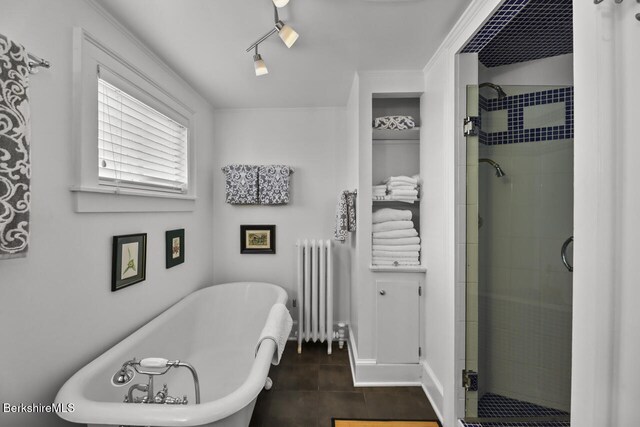 full bath featuring a shower stall, tile patterned flooring, radiator heating unit, and a soaking tub
