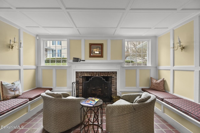 living room with coffered ceiling, a decorative wall, and a fireplace