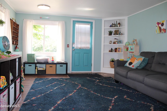 living room featuring hardwood / wood-style floors, built in features, and crown molding