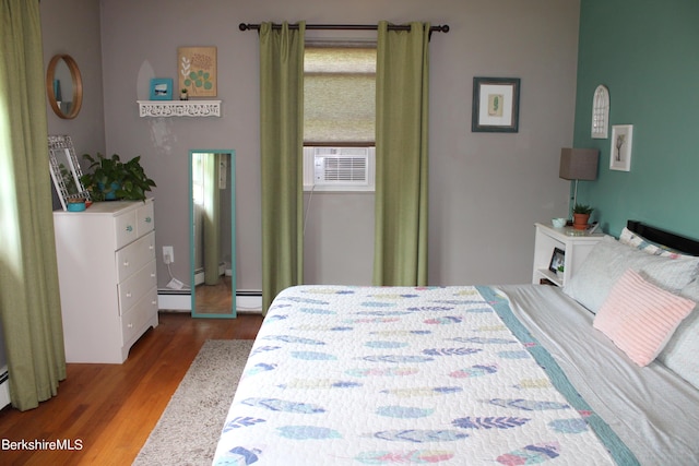 bedroom featuring cooling unit, wood-type flooring, and a baseboard heating unit