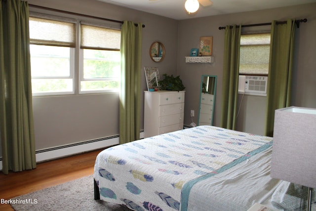 bedroom with wood-type flooring, a baseboard radiator, ceiling fan, and cooling unit