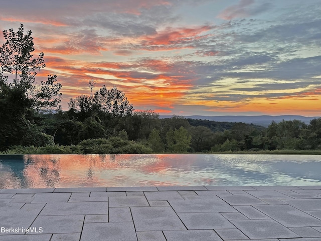 view of pool with a water view and a patio area