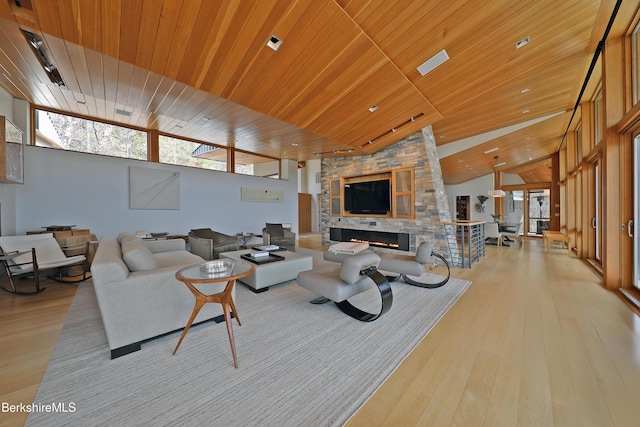 living room featuring a stone fireplace, wood finished floors, wood ceiling, and a healthy amount of sunlight