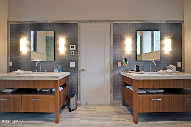 bathroom with a sink, tile walls, and two vanities