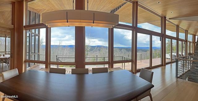 unfurnished dining area with a wall of windows, wood finished floors, a mountain view, and wooden ceiling