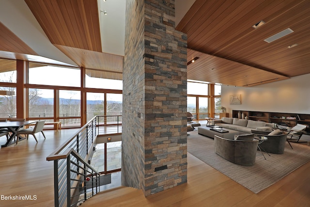 living room featuring light wood finished floors, a mountain view, wooden ceiling, and a wall of windows