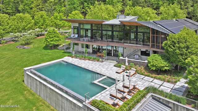 113 Brush Hill Rd, Great Barrington, MA 01230 - rear view of house featuring a patio area, a pool with connected hot tub, a sunroom, a yard, and a view of trees