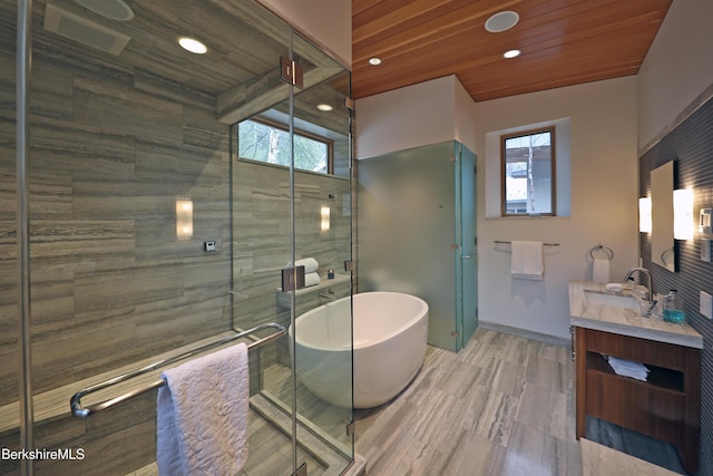 full bathroom with wood ceiling, a shower stall, vanity, and a freestanding tub