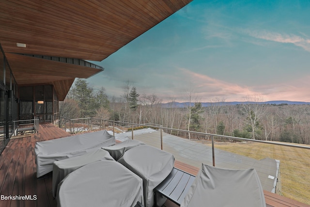 deck at dusk featuring a mountain view and a forest view