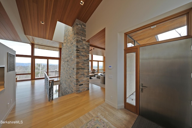 entryway featuring high vaulted ceiling, wood ceiling, light wood-style flooring, and ornate columns