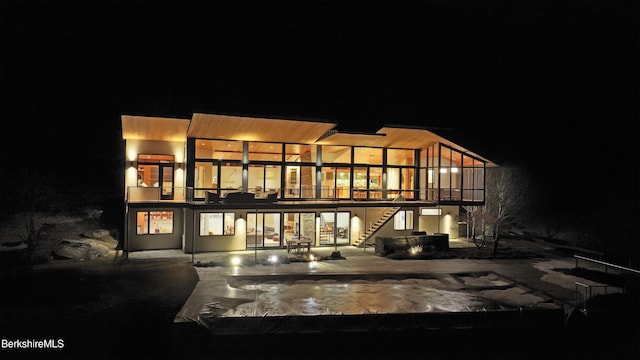 back of house at night featuring stairs and a patio