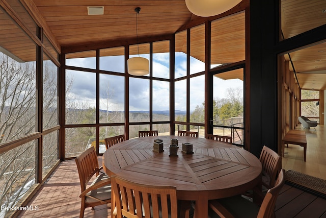 sunroom / solarium featuring a mountain view, plenty of natural light, and wooden ceiling